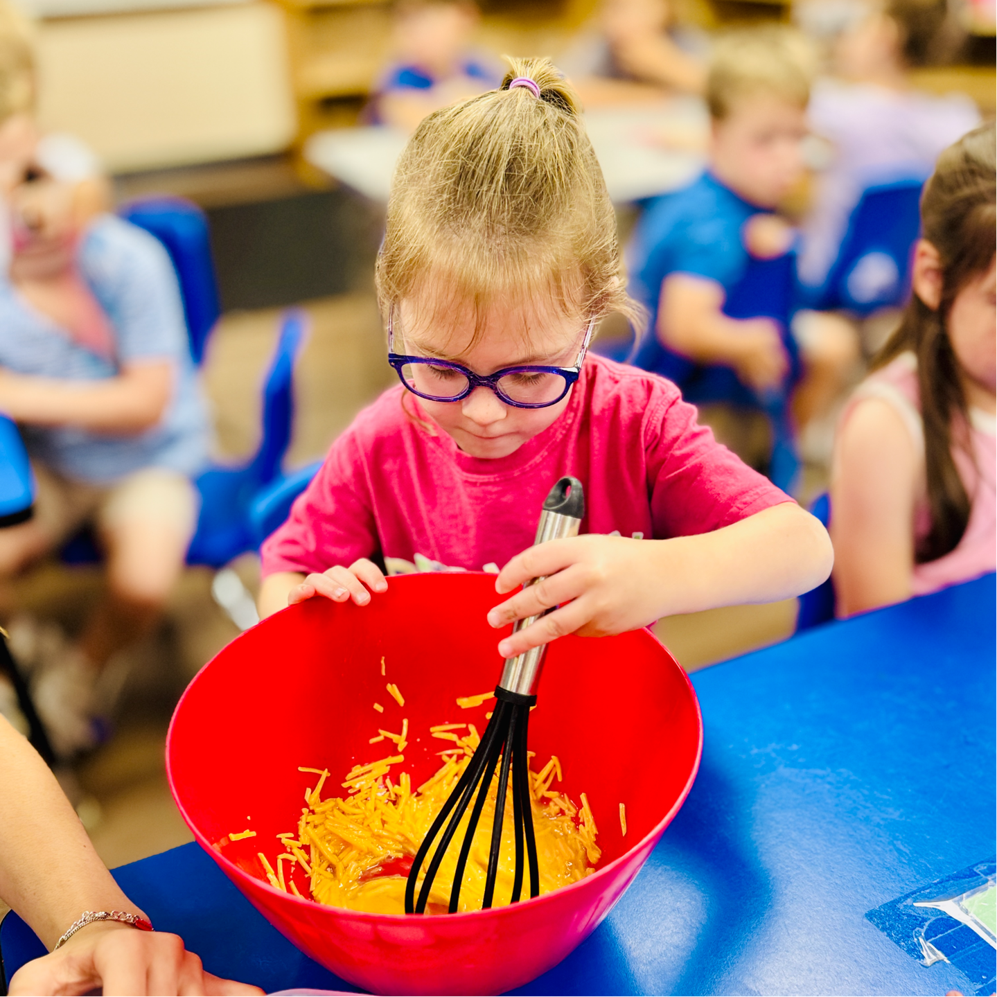 Preschool child stirring a bowl of food at camp.