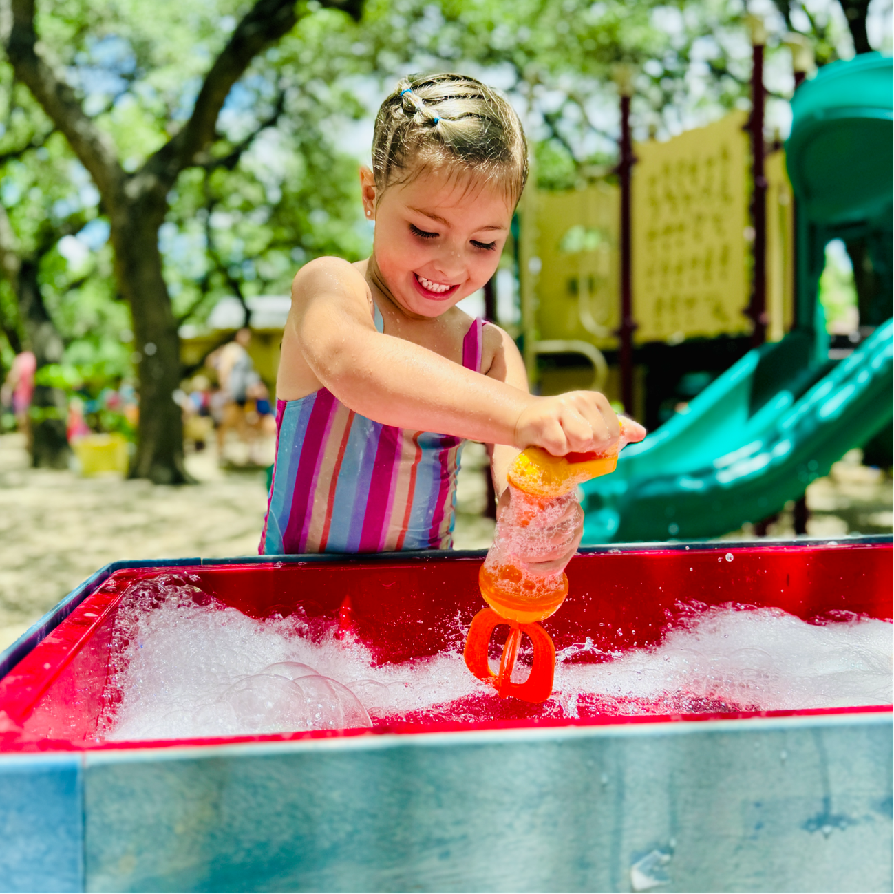 Preschool child doing water play fun at summer camp.
