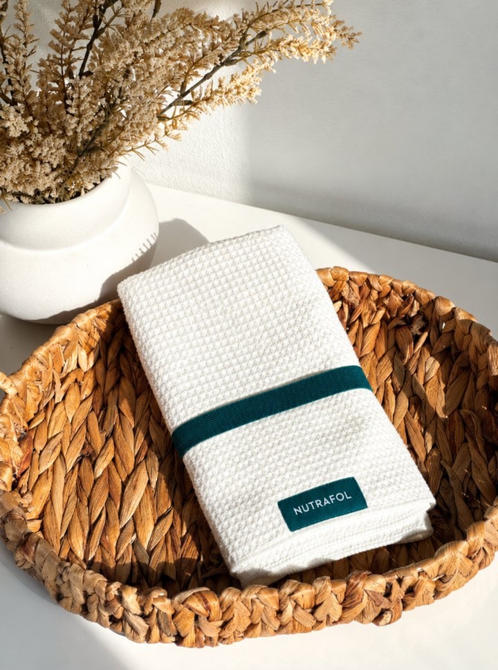 Nutrafol microfiber hair towel in a woven basket