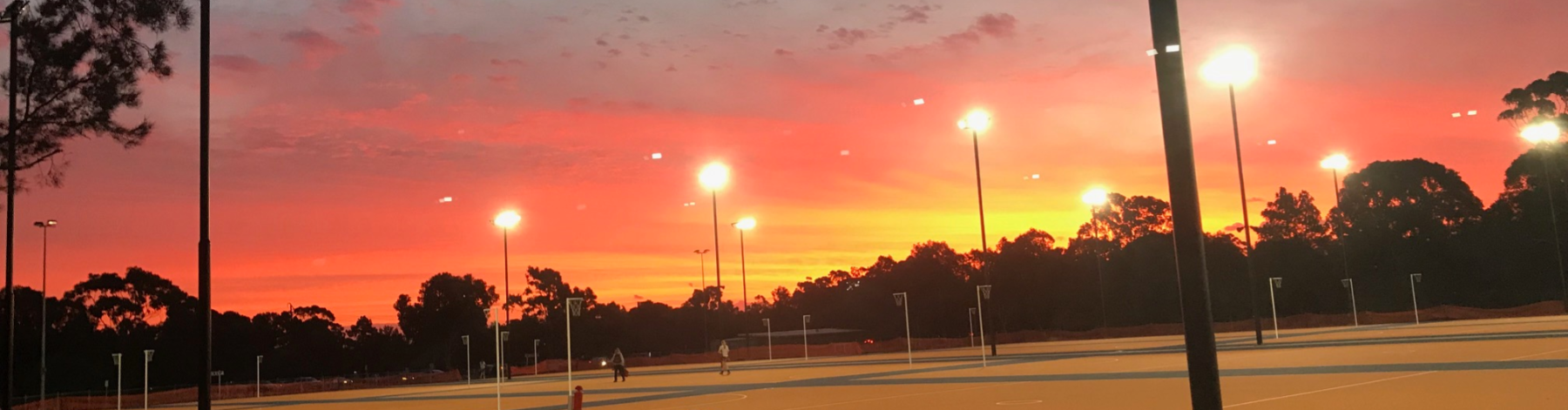 Netball courts with a bright orange sunset in the background