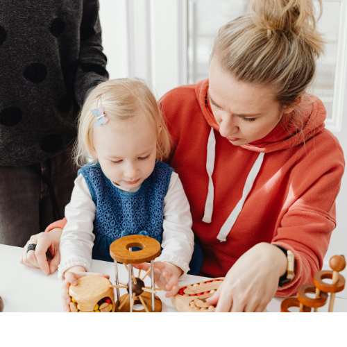 Mother and young child engaging in interactive, screen-free learning using wooden toys and manipulative play materials.