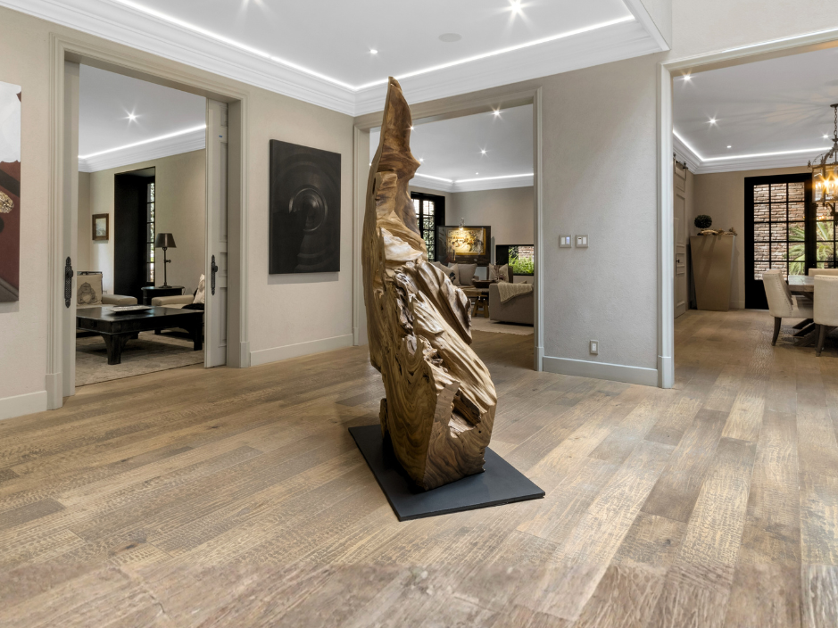 Casa en Lomas de Chapultepec, Triángulo Dorado de Chapultepec.  Interior de residencia de lujo en Lomas de Chapultepec con diseño contemporáneo, pisos de madera natural, iluminación arquitectónica y pieza escultórica central, representativo del alto valor patrimonial de la zona.