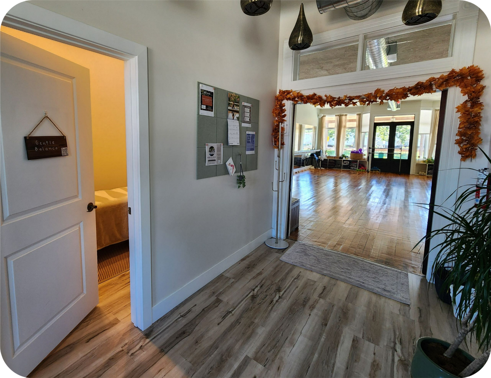 Just inside the front door is a nice hallway with some fall garland above the entrance to the yoga studio classroom. The massage room door is open a crack on the left side, with a warm light inside