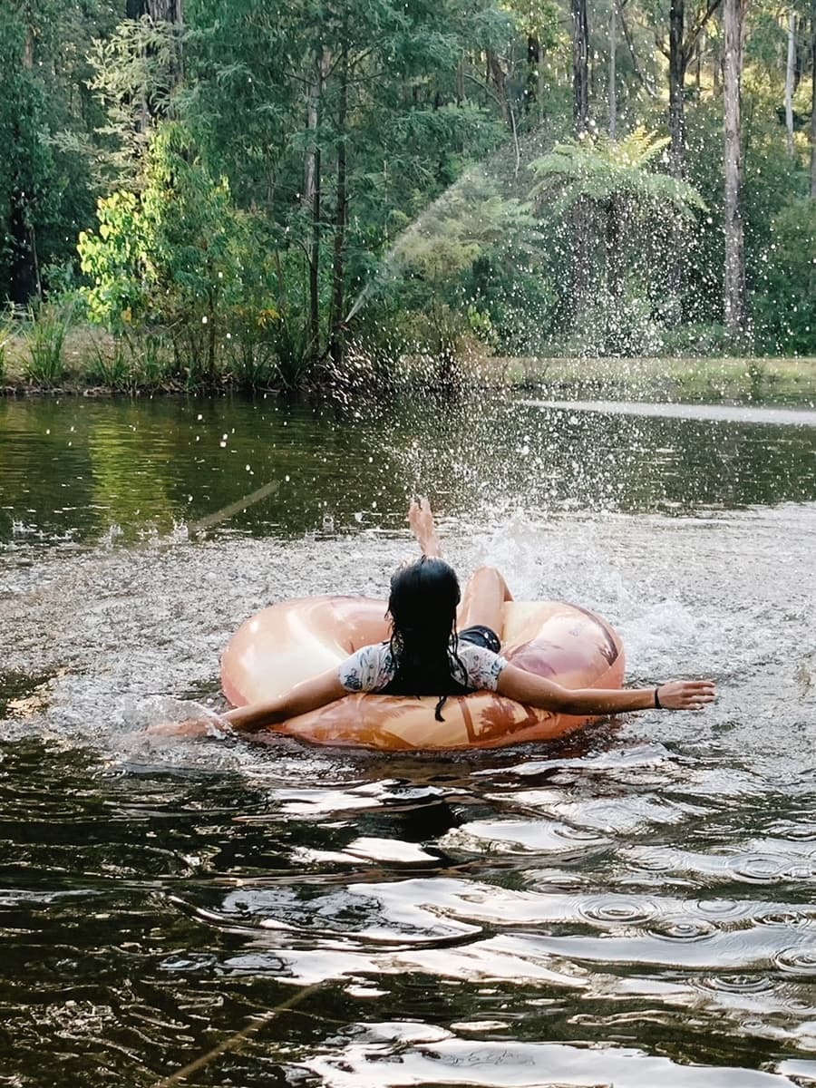 Guests enjoying a float tube near the spring-fed fountain—perfect for cooling off and reconnecting with nature at Andersons Eco Retreat