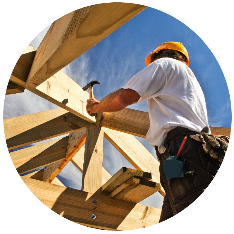 man in a hard hat holding a hammer working on framing a house
