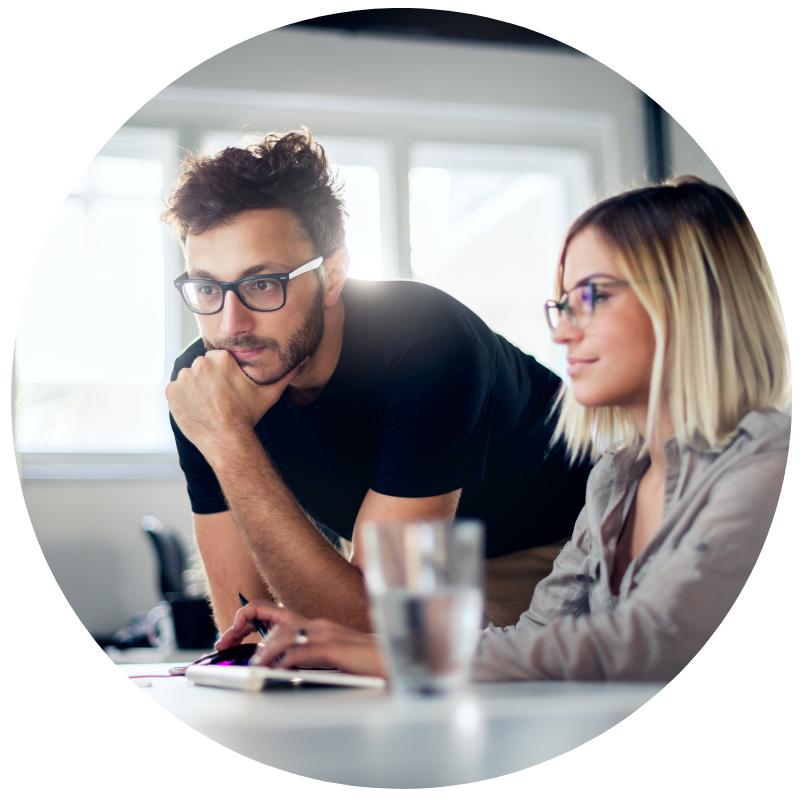 Two office workers looking at a computer screen.