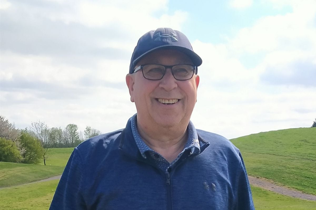 Smiling older golfer in a cap and glasses standing on the course
