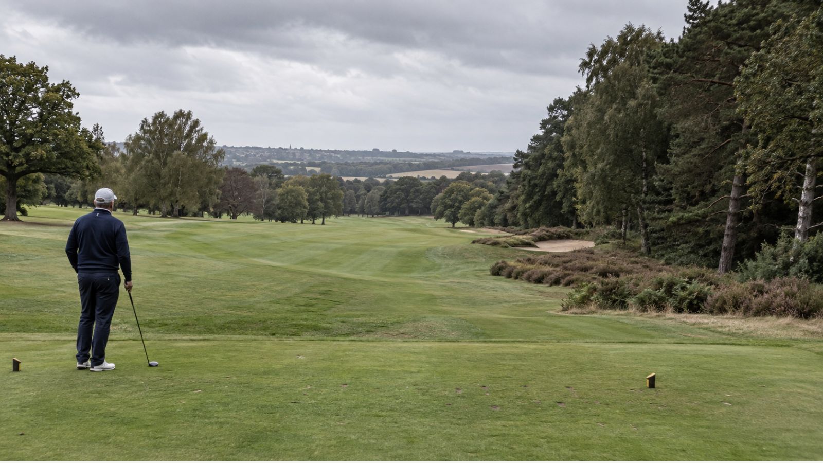 Older golfer on a UK tee looking down a fairway with more room on the safer side