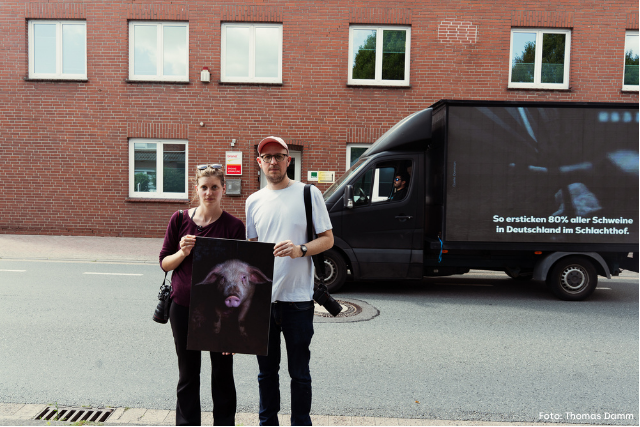 Anna und Hendrik stehen vor dem Brandenburger Tor mit dem Video-LKW und einem Schild in den Händen: