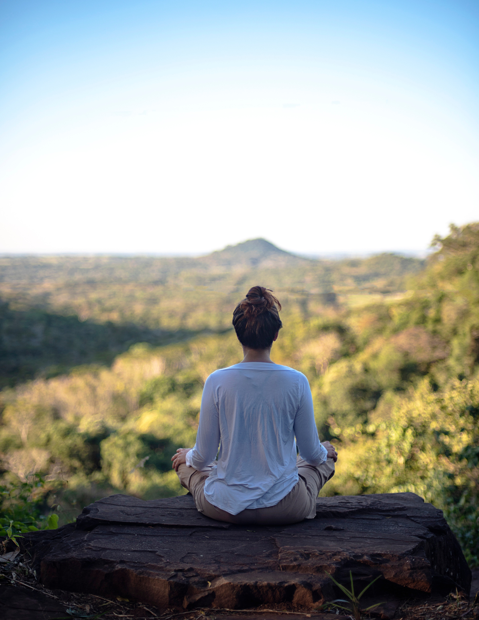 Person sitting peacefully on wooden dock at sunrise, reflecting during transformative travel coaching session