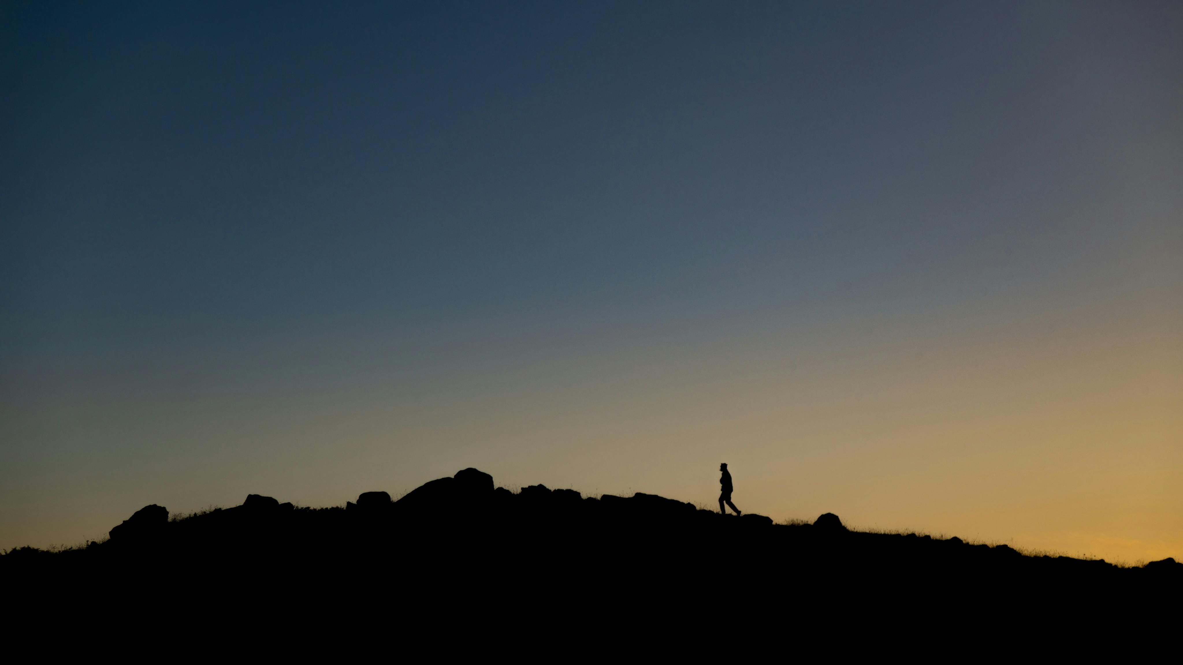 Man walking on top of a mountain contemplating healing travel transformation and renewal