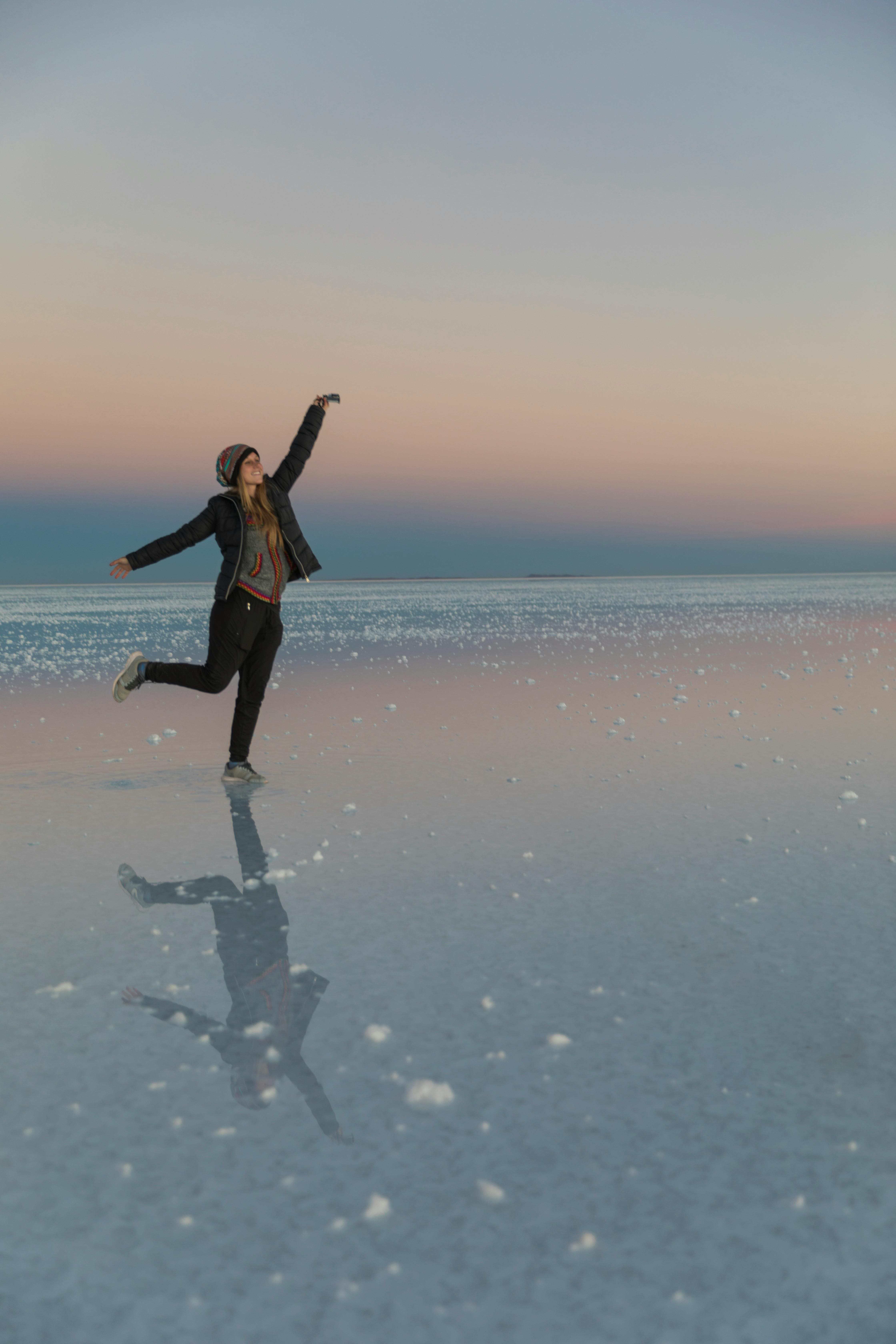 Woman jumping with reflection in desert landscape during travel memory excavation and self-discovery coaching