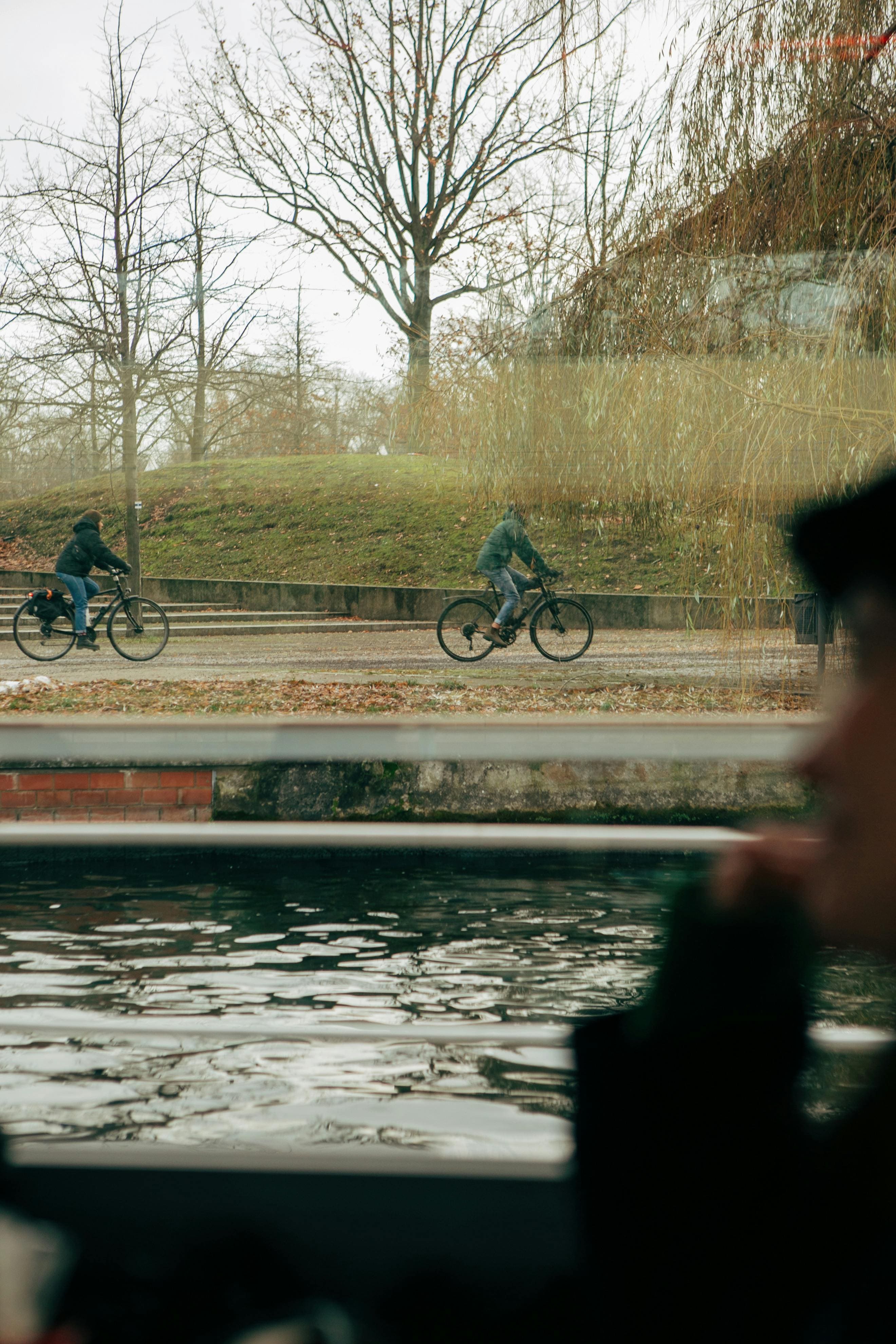 Person's silhouette in bus window observing city cyclists, integrating travel insights into daily life coaching