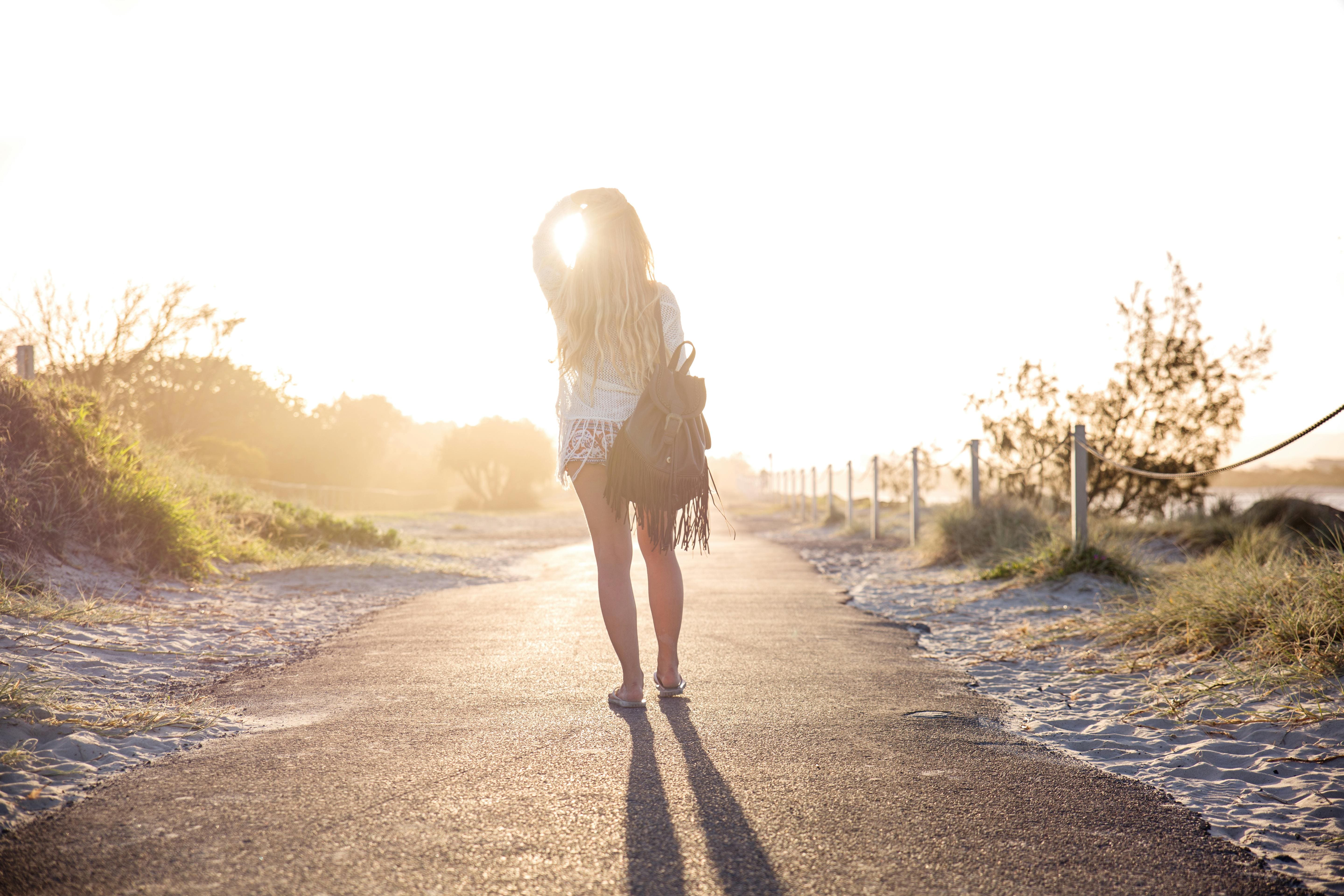 Woman staring at the sunrise, overlooking peaceful road during intentional travel healing trip