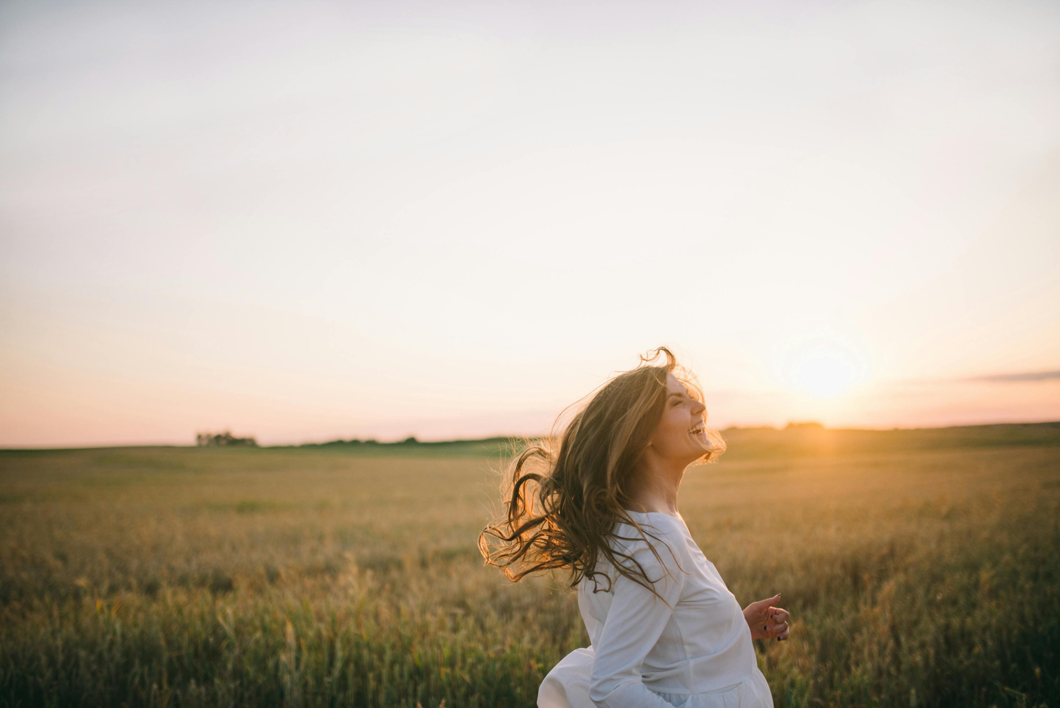Woman running happy on top a field contemplating healing travel transformation and renewal