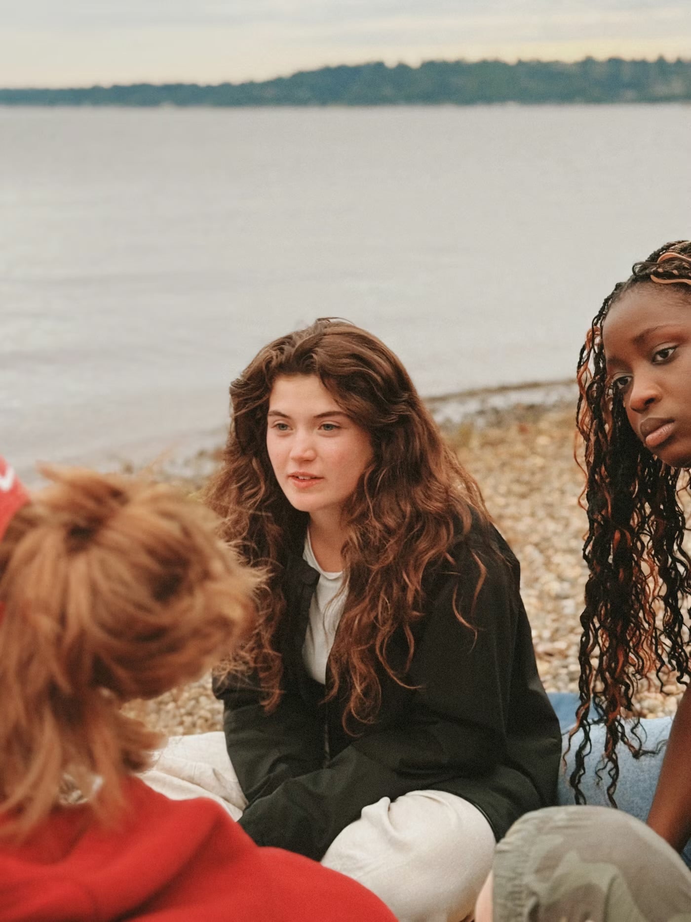 Young women engaging in discussion on a lakefront beach