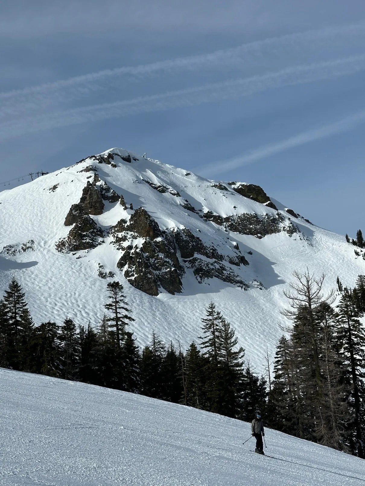 Snow-covered mountain terrain with a skier below the ridge