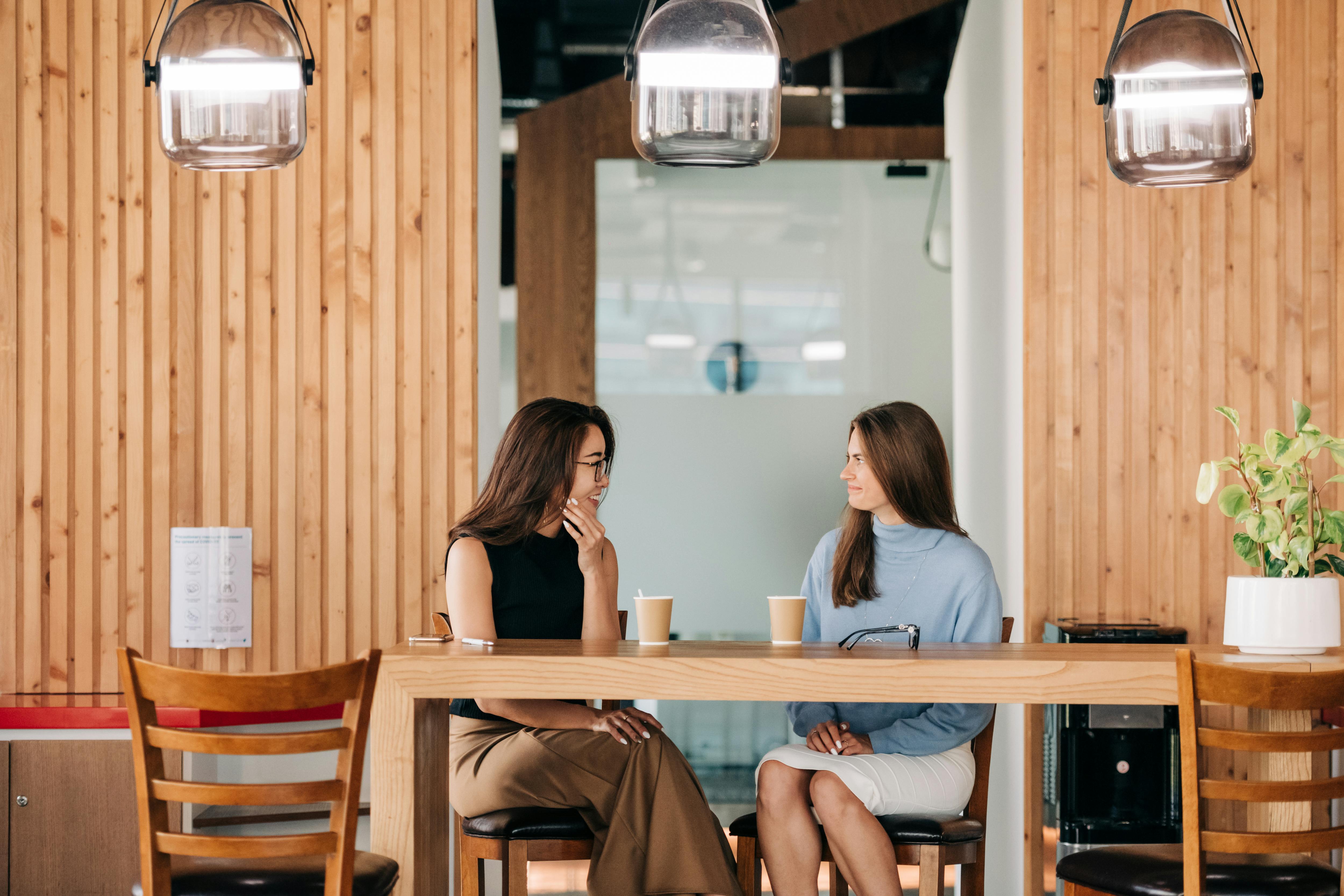 Two women are having a coffee in a modern cafe.