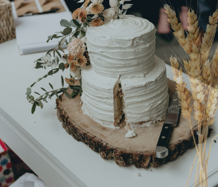 2-tier wedding cake on slab of wood with cutting knife next to it.