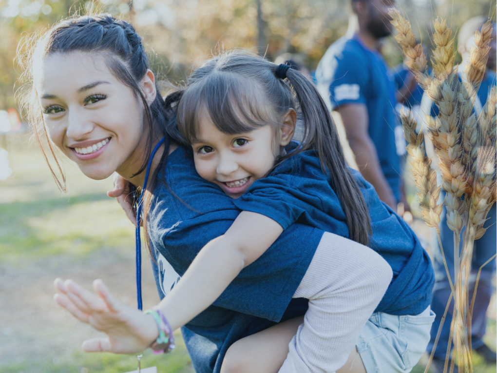 Teen carrying young girl on her back at an event.