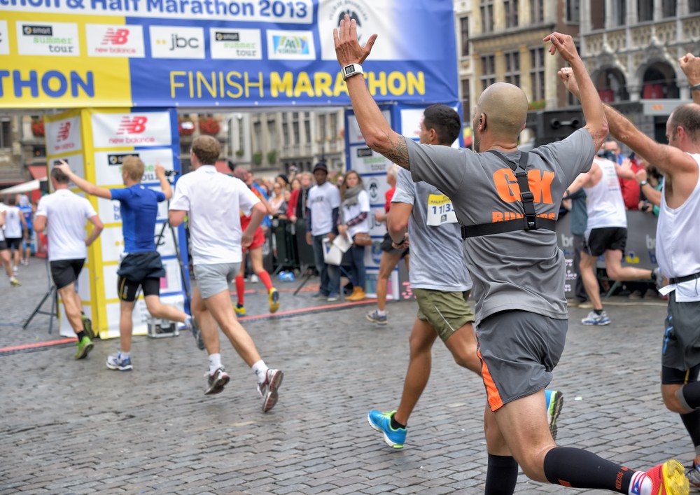 Marathon runners raise their arms as they cross a city finish line during a public race.