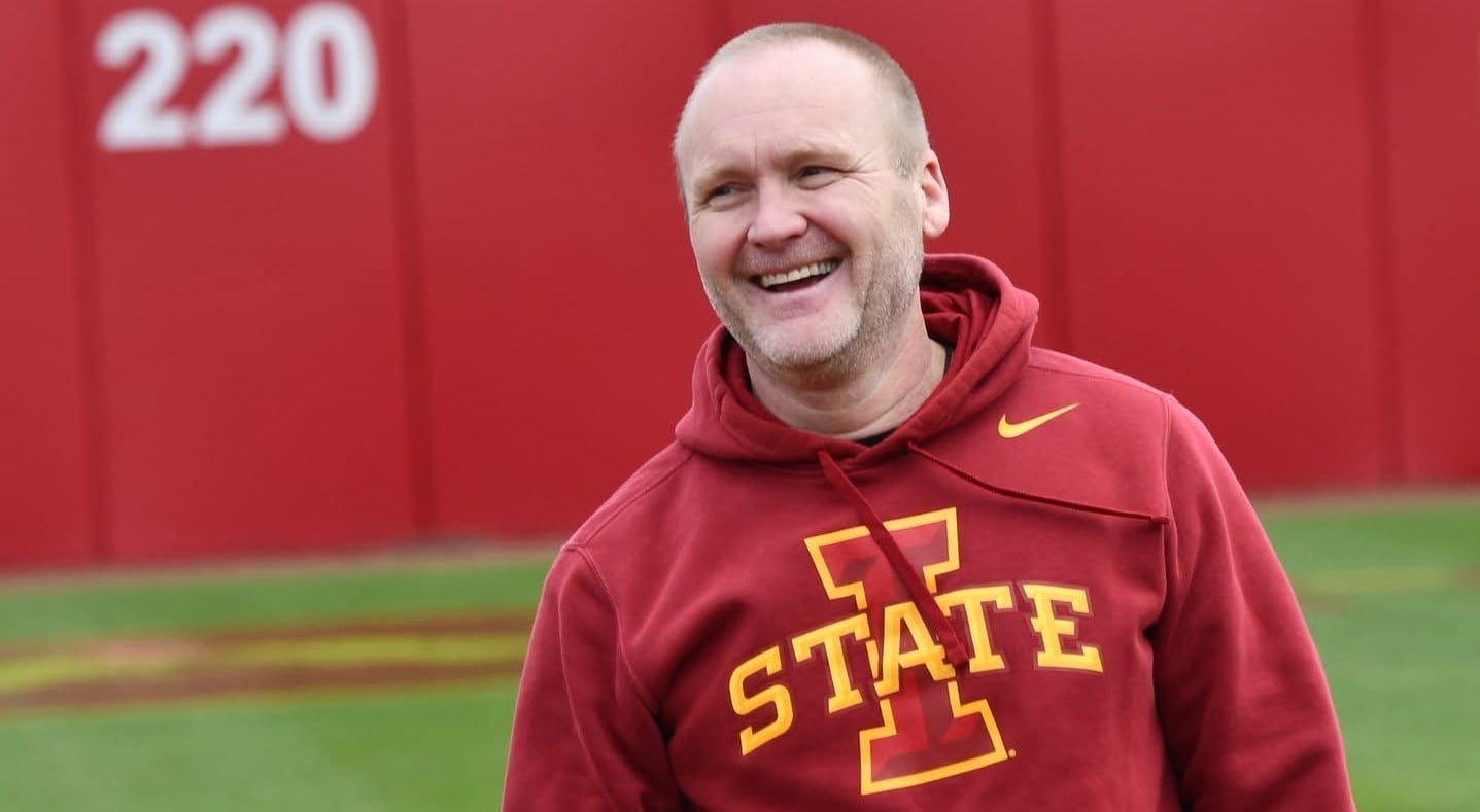 Chad Brown laughing in a red Iowa State hoodie on the Iowa State softball field.