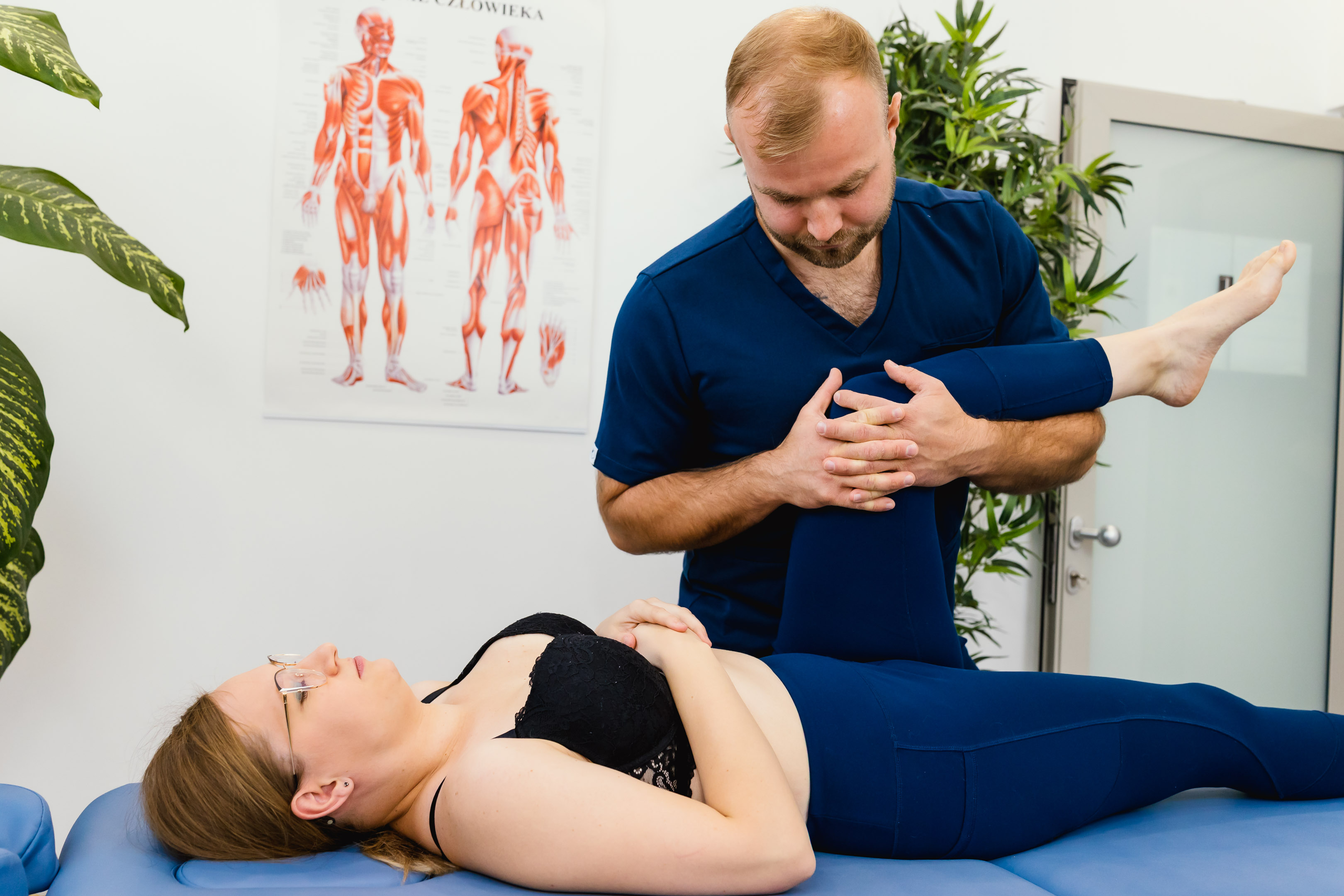 Fizjoterapeuta przeprowadzający mobilizację stawu barkowego pacjentki leżącej na stole.
