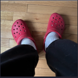 Red Crocs on feet, on the floor