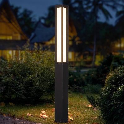 Modern LED outdoor bollard light illuminating a landscaped garden path at night with warm ambient lighting near contemporary homes.
