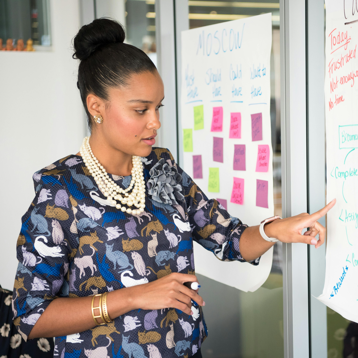Professional woman points at product flow on wall