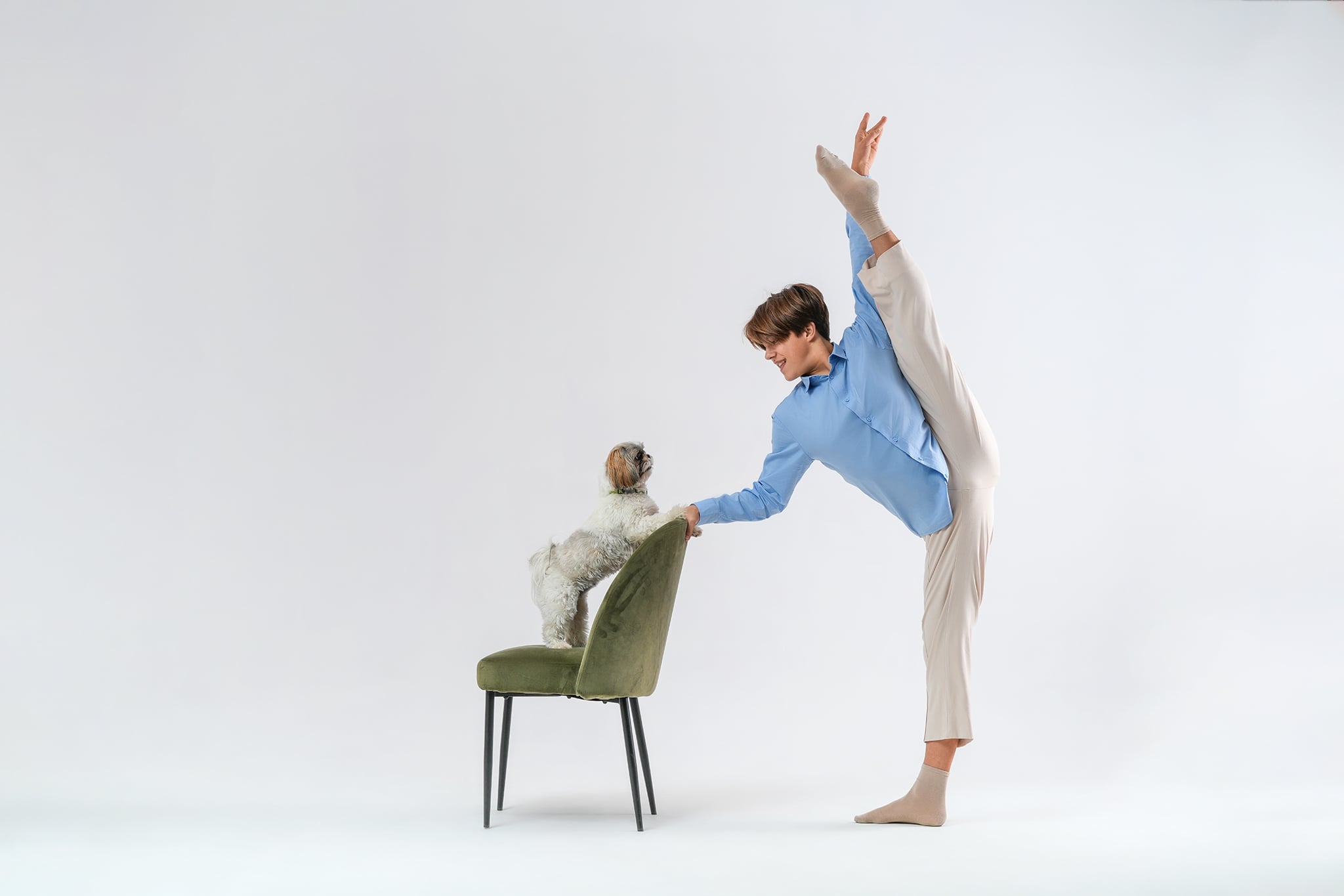 tancerz w wysokim arabesque z psem na krześle – artystyczna fotografia tańca i psów w studio