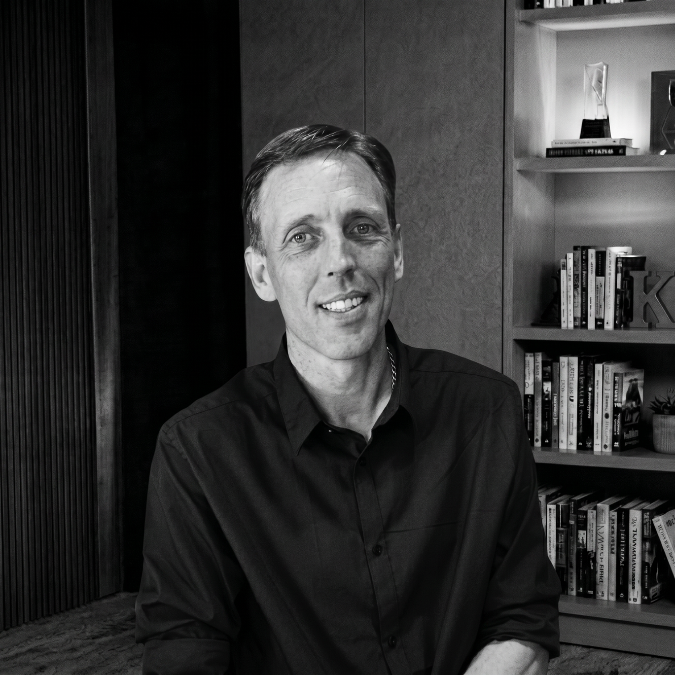 Profile block on a black background titled 'Nicolai Hyllested, Architect & Technical Co-Founder: Mapping the AI Nervous System'. On the left is a black and white portrait of Nicolai Hyllested smiling in front of a modern bookshelf. The text to the right outlines a quote on sensing behavioral intent and micro-deviations, followed by an explanation of his core innovation, Residual Stream Cartography. Below the text is a pink button reading 'Connect with Nicolai'.