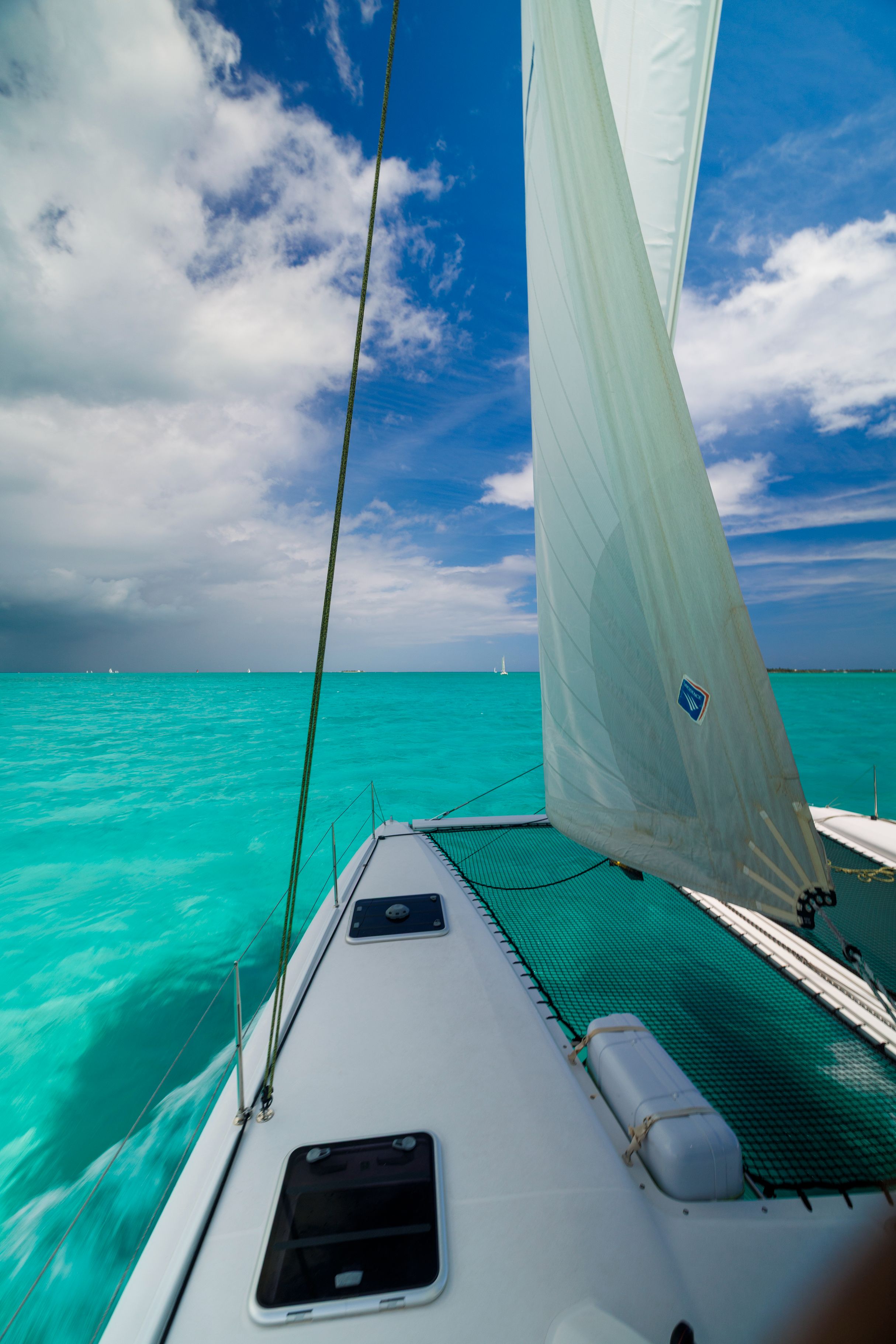 View from the forward deck of a 2016 Outremer 45 performance cruising catamaran sailing through turquoise waters in the Bahamas.