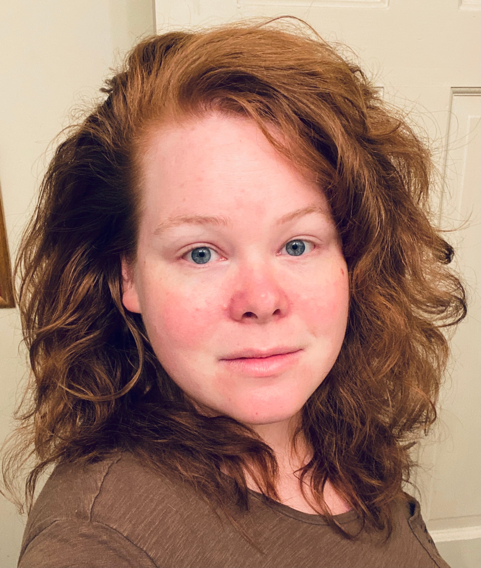 A photo of Erika, a white person with shoulder length red hair and blue eyes.