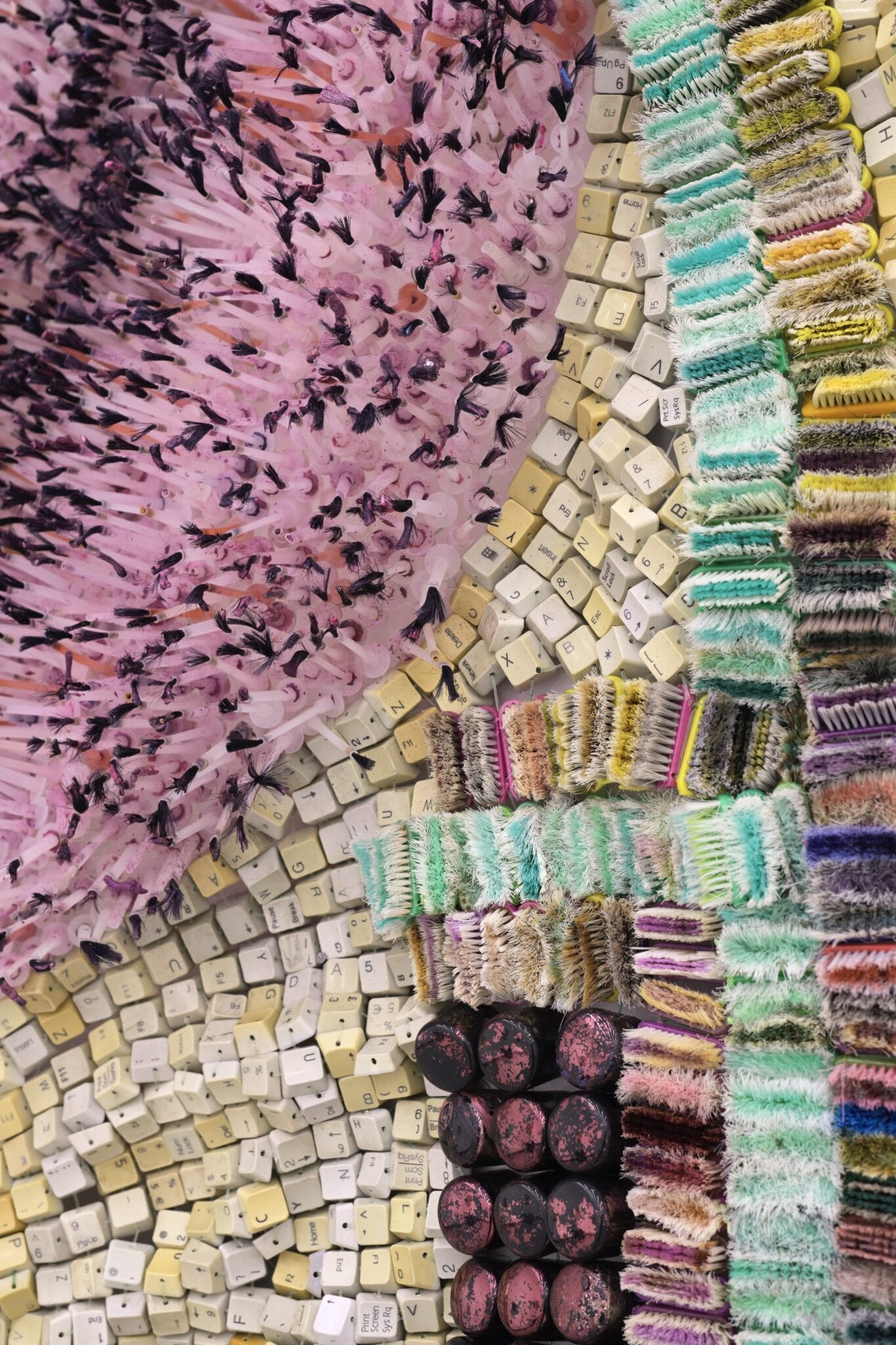 a detail of an abstract wall-installed artwork by Moffatt Takadiwa made from computer keyboard keys, combs, toothbrush heads, and metal pieces