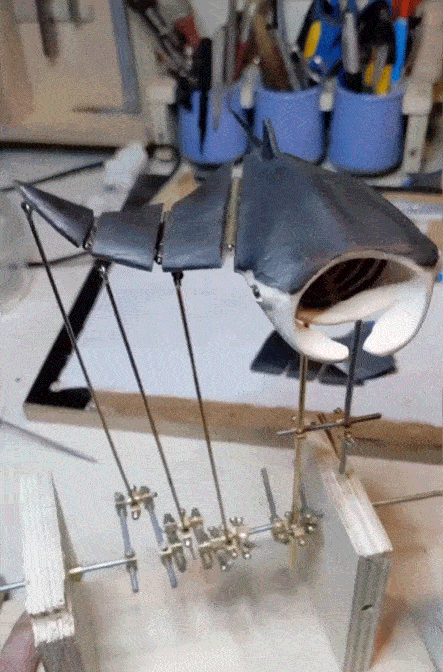 A gif of a kinetic sculpture with gilded appendages and moving, white pieces resembling insects and flwoers.