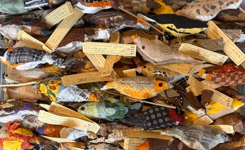 a group of dozens of handmade fabric birds with paper tags identifying them, modeled after real birds