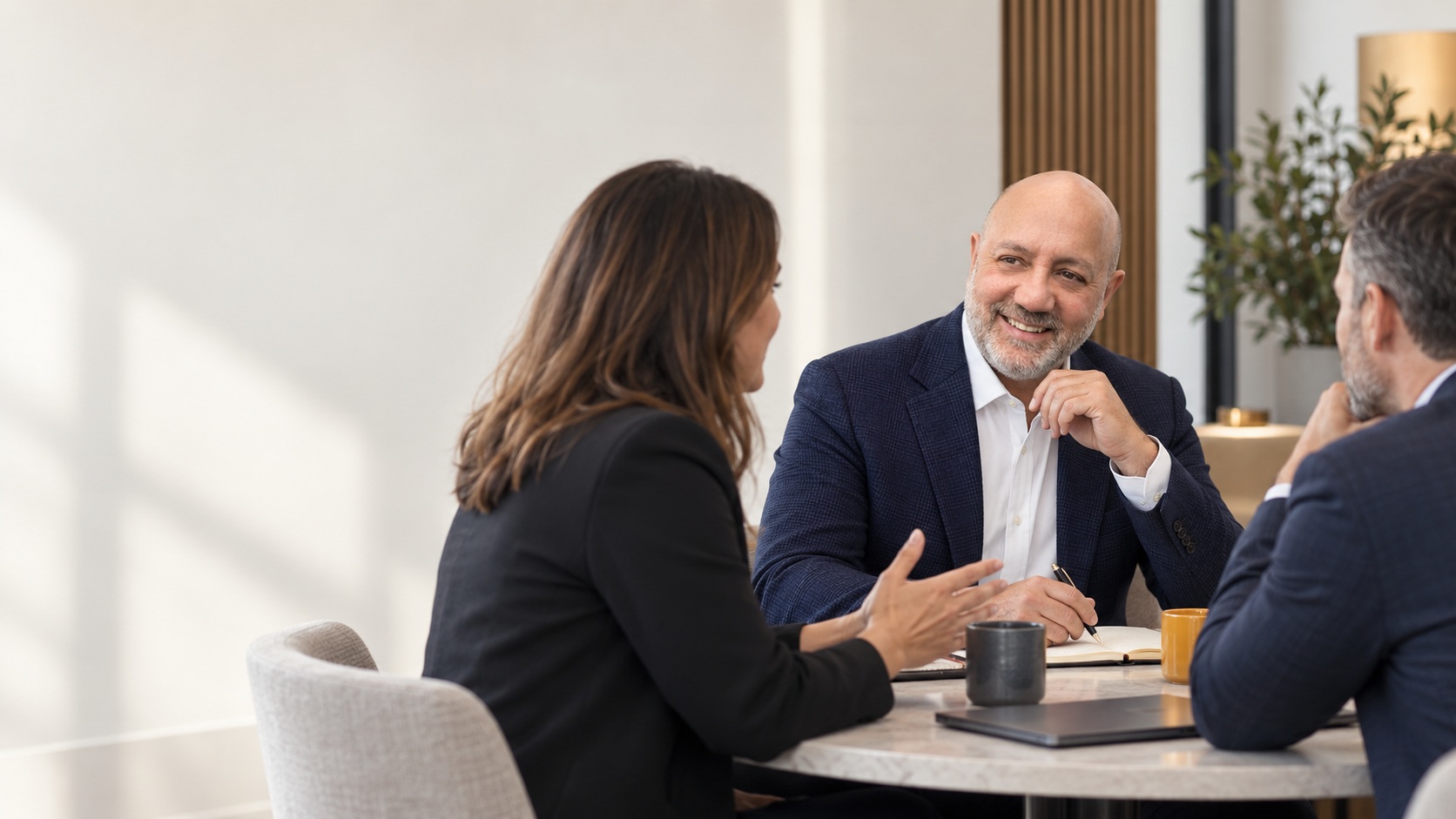 Andre Malowney in discussion with two colleagues around a small table, taking notes