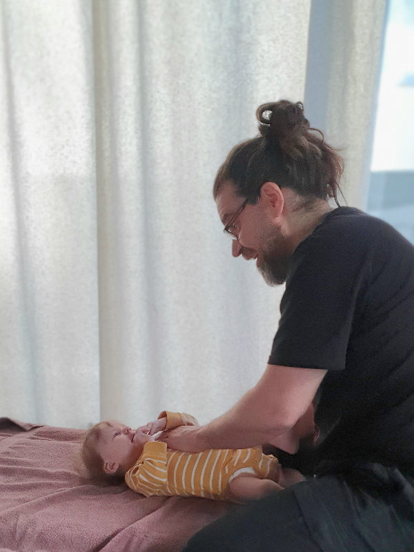 Osteopaatti Jari Kauppila hoitaa vauvaa hierontapöydällä