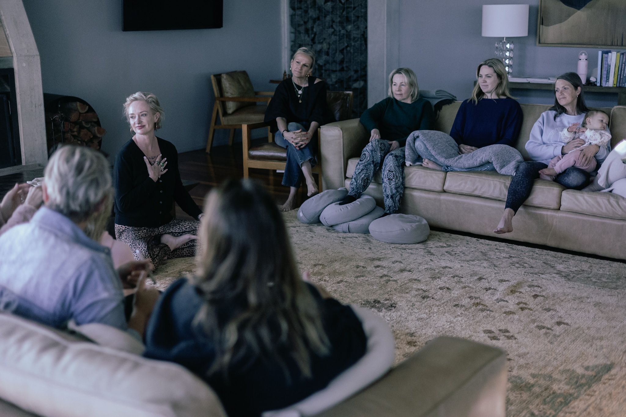 A facilitator speaking to women gathered in a lounge room