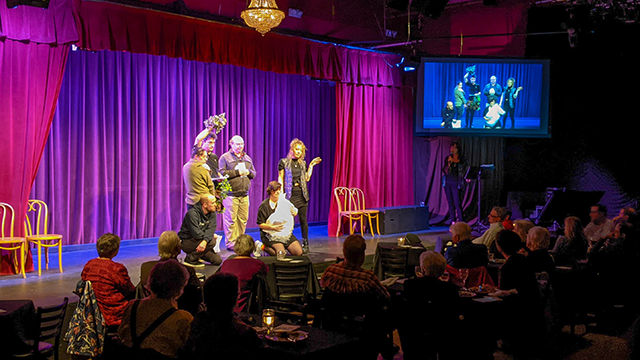 Actors appear on stage during a hybrid event benefiting an arts organization.