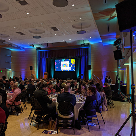 Attendees enjoy dinner in a ballroom just before the start of the program during a hybrid event