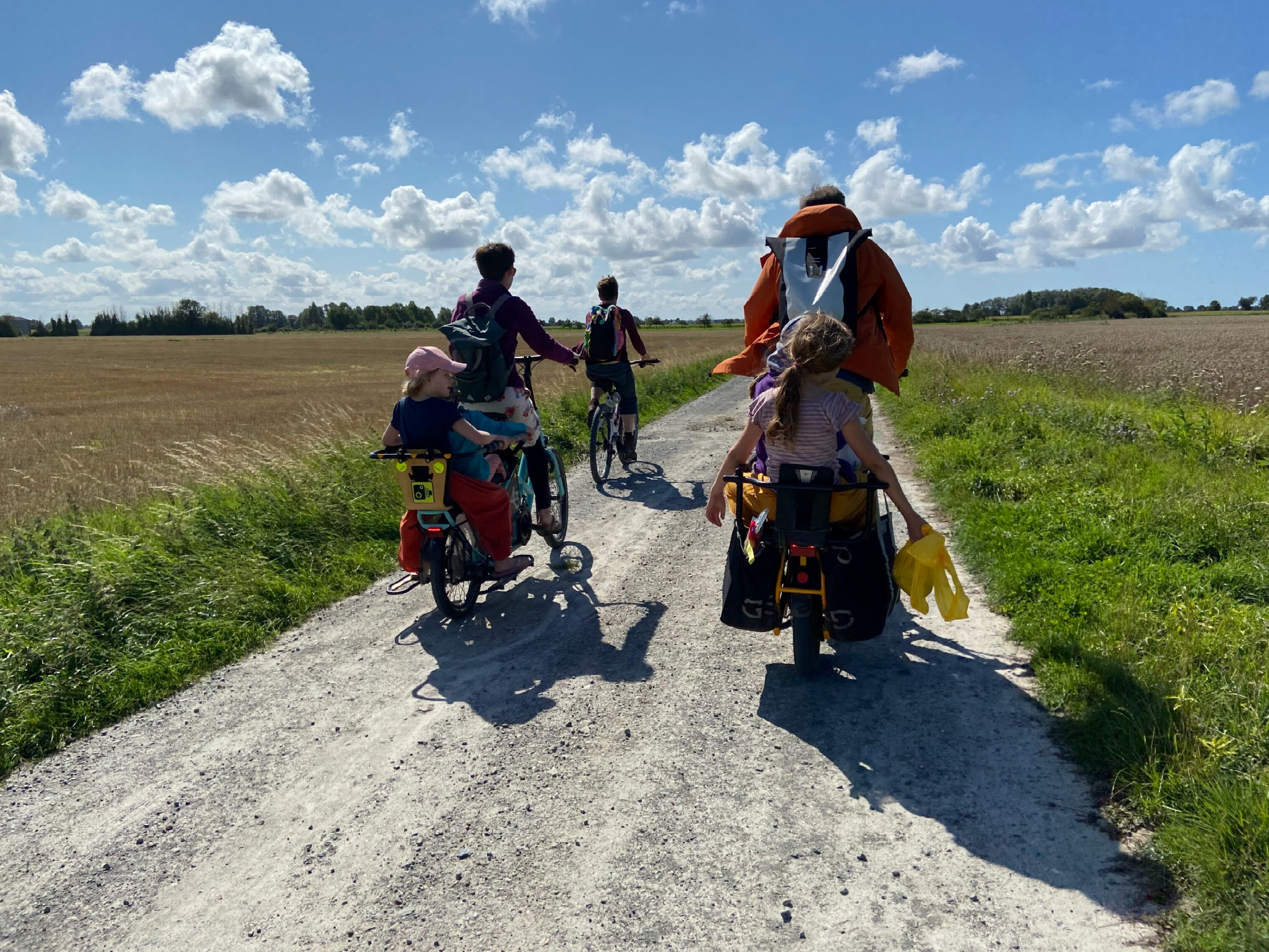 family of cyclists cycling on a gravel track on a sunny day
