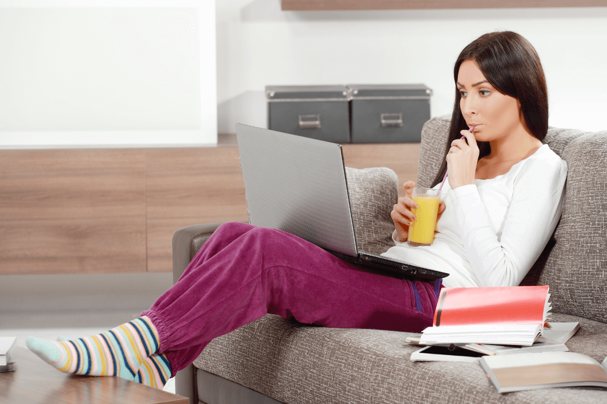 A woman relaxes on the couch with her laptop on her lap.