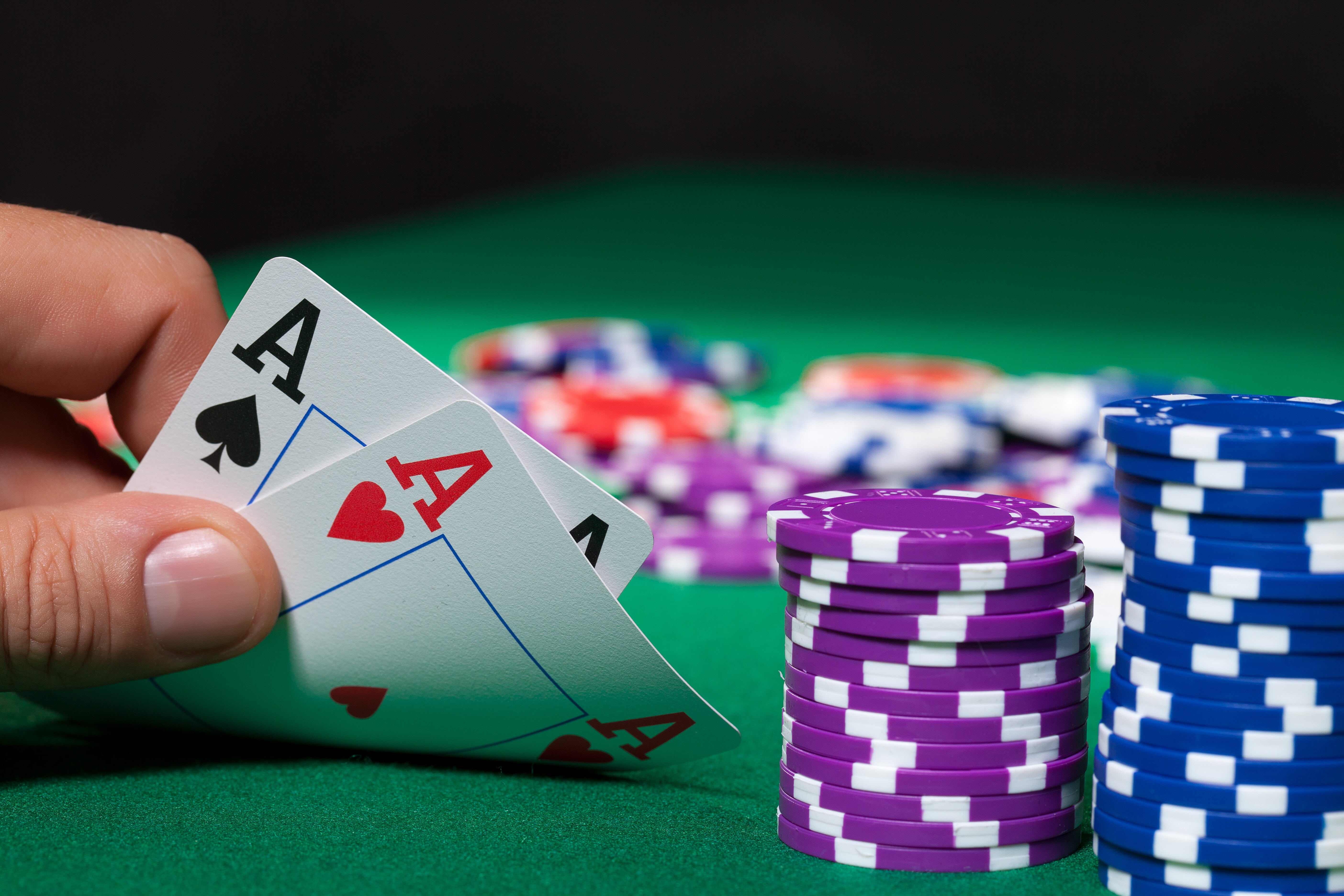 Colorful poker chips and pocket aces, someone showing their hand