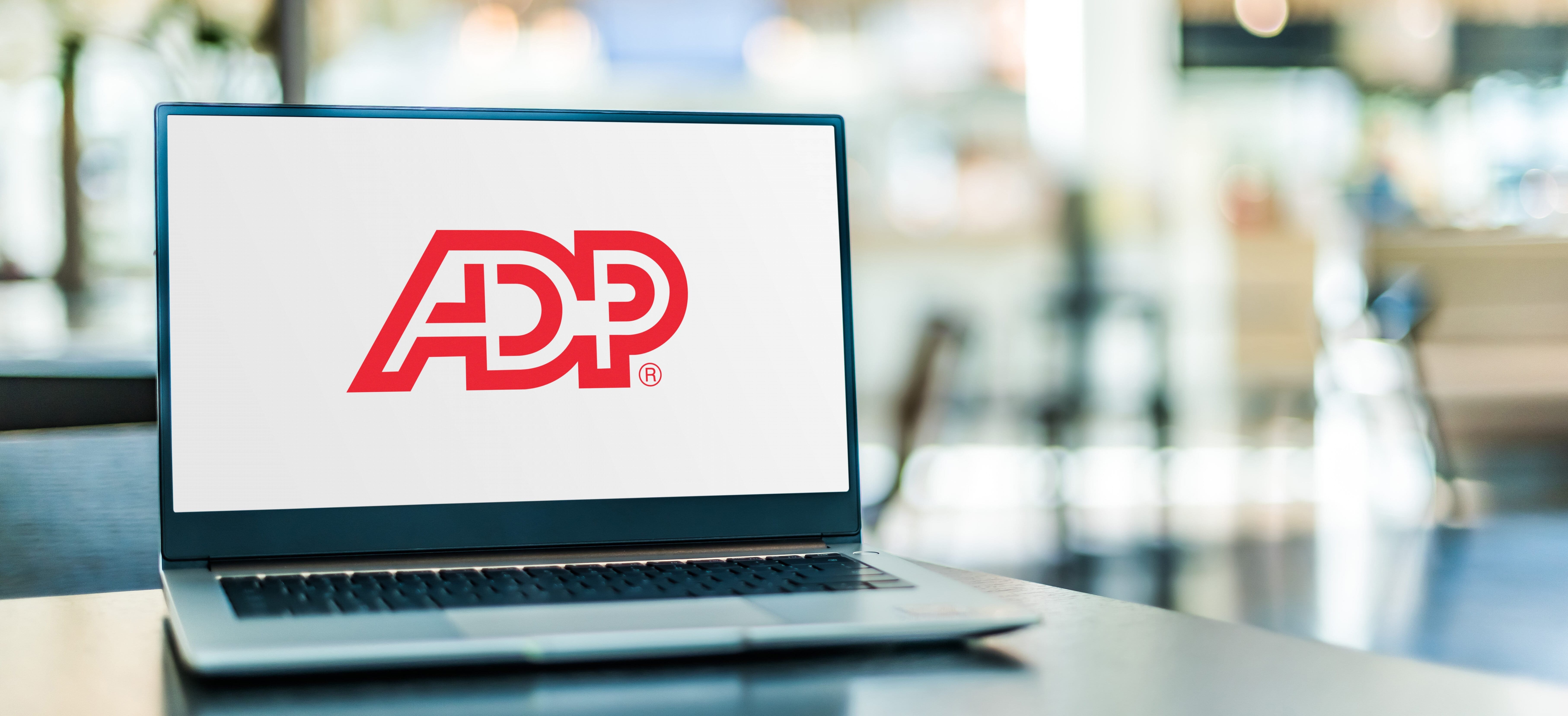 ADP logo on a laptop that's placed on a desk in an office