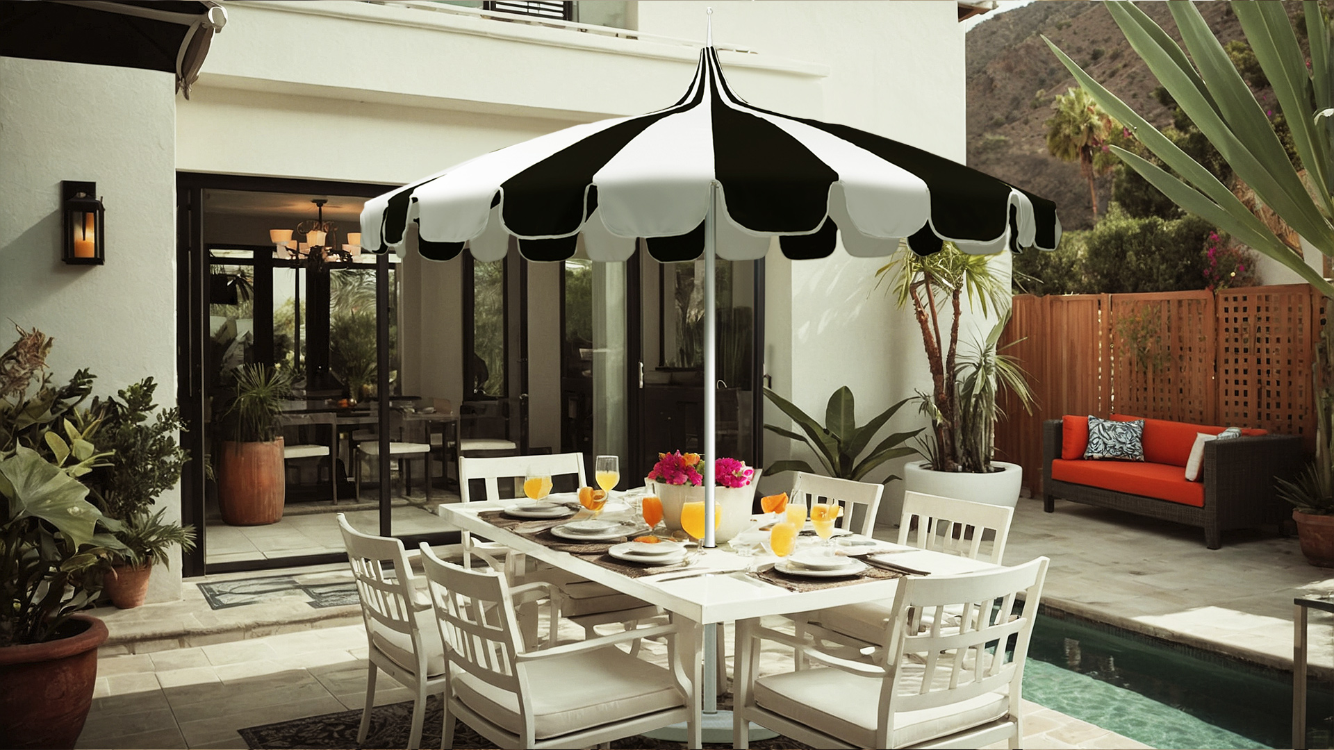 A black and white Pagoda Series umbrella from California Umbrella provides shade over a stylish outdoor dining area, creating an elegant setting by the pool.