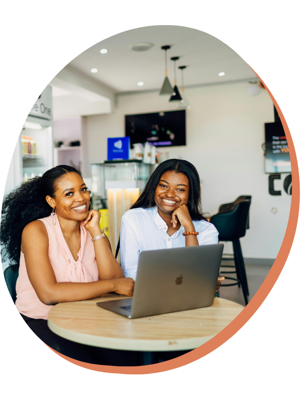 Woman with braids working on her phone with laptop in front - dream catch consulting