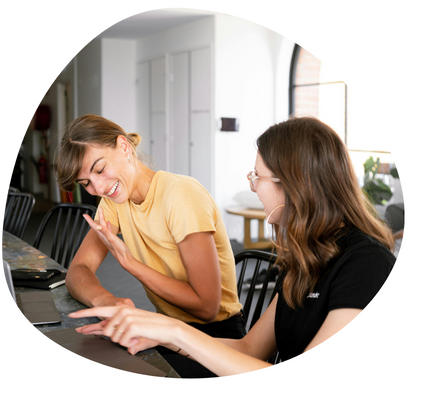 Two women smiling and laughing at computer