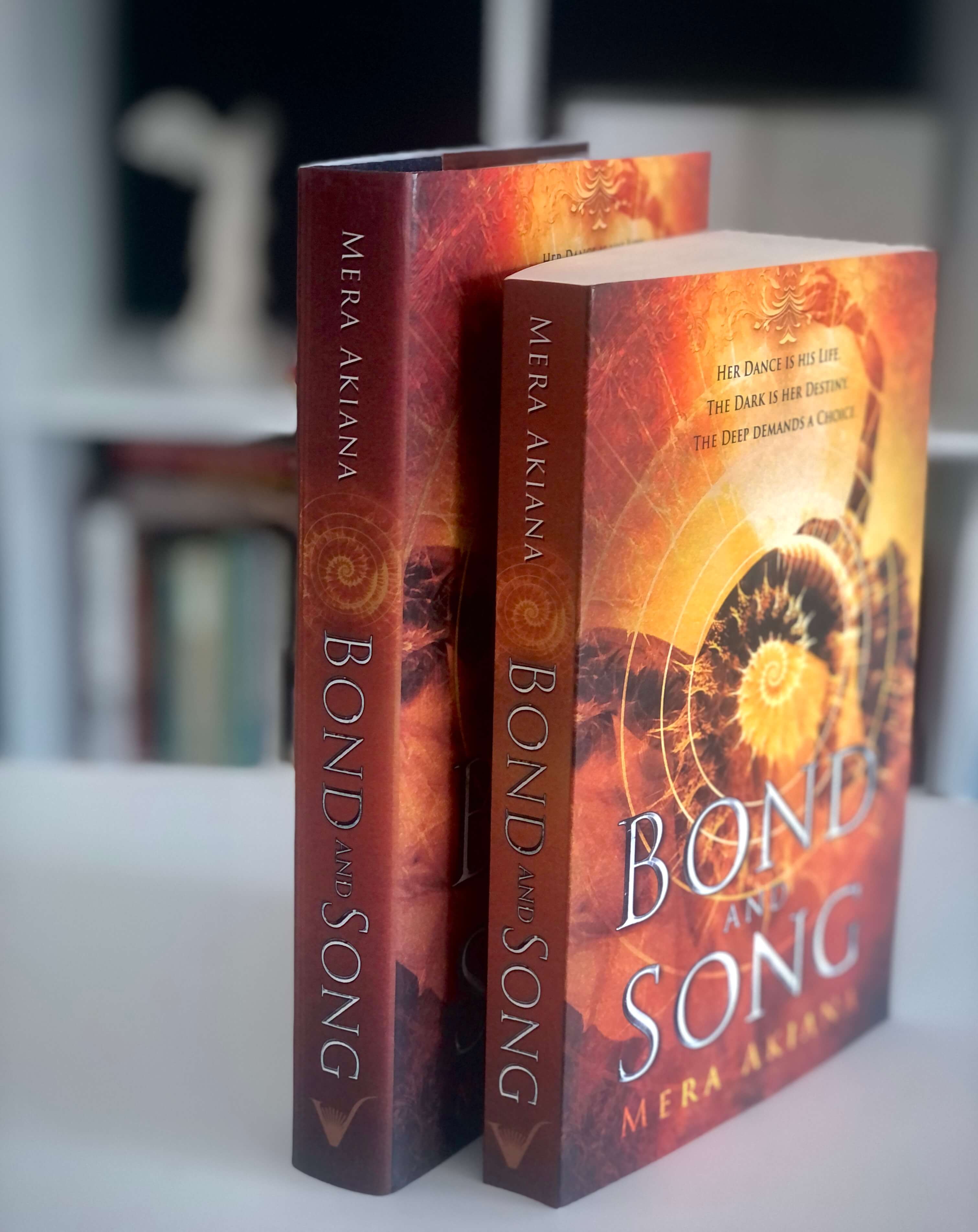 view of spines and front cover of Bond and Song paperback and hardcover next to one another
